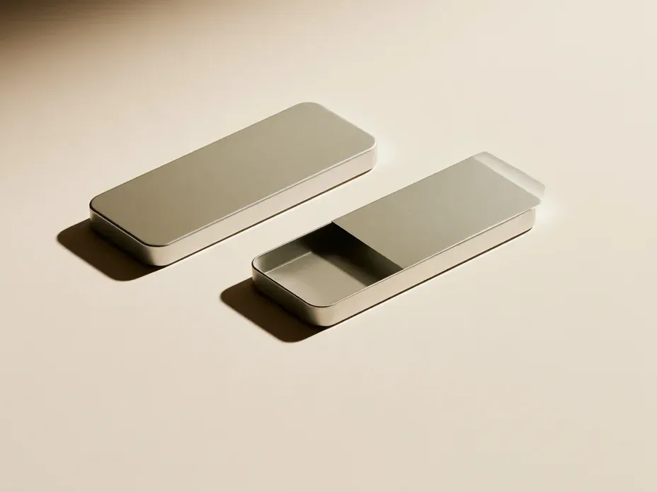 Two slim rectangular metal tins side by side, one closed and one with its slide-top lid pushed partly open.